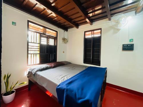 sypialnia z niebieskim łóżkiem w pokoju z oknami w obiekcie Bhumi w mieście Pulpally