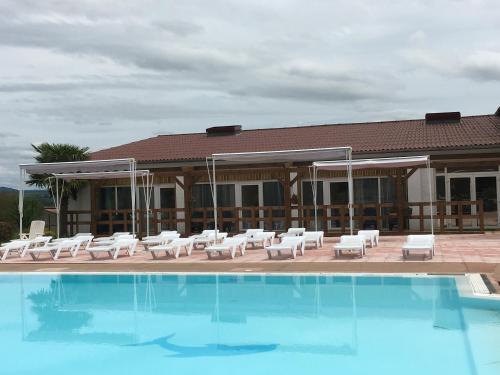 una piscina con tumbonas blancas y un edificio en Hôtel Restaurant - Le Vieux Pigeonnier en Loubressac