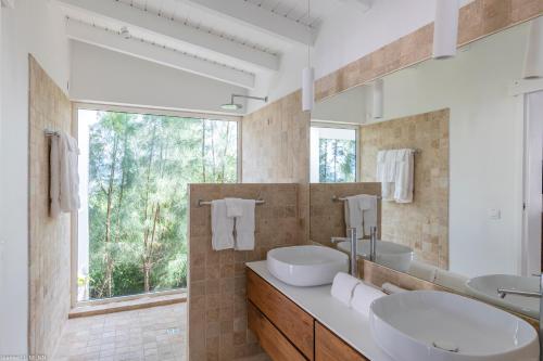 ein Badezimmer mit zwei Waschbecken und einem großen Fenster in der Unterkunft O SUN in Les Terres Basses