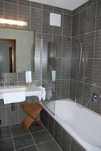 a bathroom with a tub and a sink and a shower at Apart Ideal in Lermoos