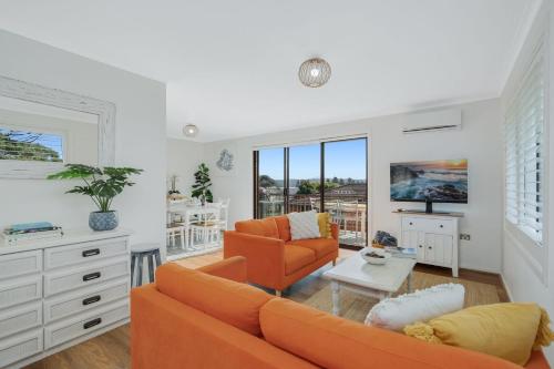 a living room with an orange couch and a table at Bermagui Townhouse - Amazing views & location in Bermagui