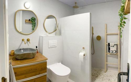 bagno con lavandino, servizi igienici e specchi. di Marina Sunrise a La Herradura