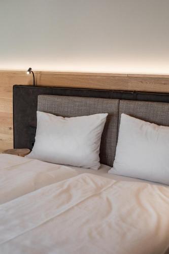 a bed with two white pillows on top of it at Hotel Salzburg in Saalbach Hinterglemm