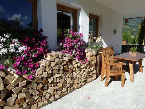 a retaining wall with a table and chairs and flowers at Apart Ideal in Lermoos