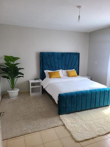 sypialnia z dużym łóżkiem z niebieskim zagłówkiem w obiekcie Woke w mieście Nakuru