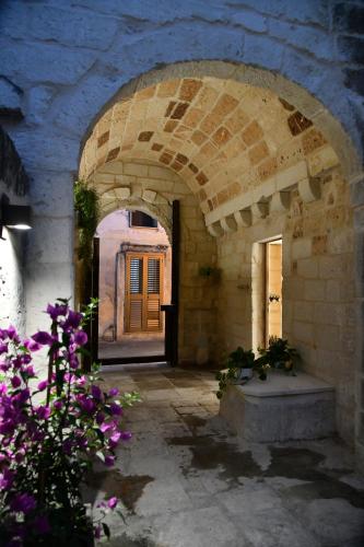 un arco in un edificio con porta e fiori di La Dimora delle Grazie a San Cesario di Lecce