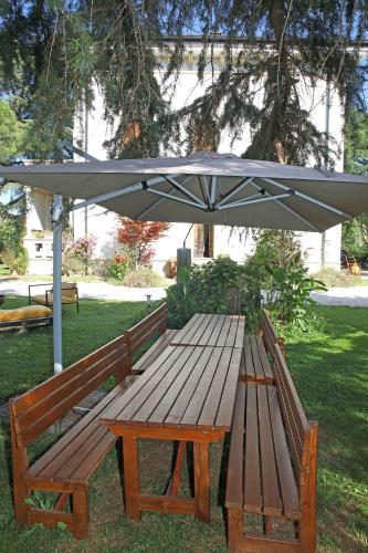 a wooden picnic table with an umbrella in a park at Il Bozzolo Eco Boutique Apartments in Valeggio sul Mincio