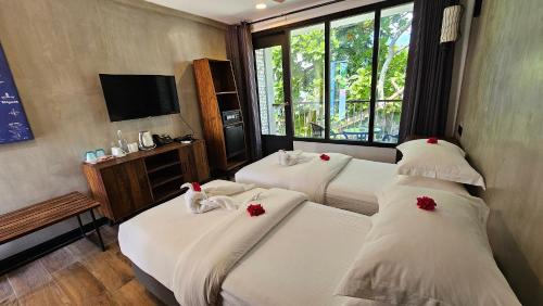 a room with two beds with red flowers on them at Dhigurah Cottage in Dhigurah