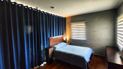 Guest House in Sucre في سوكر: غرفة نوم بسرير ونافذة مع ستائر