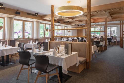 un restaurante con mesas y sillas blancas y ventanas en Hotel Salzburg en Saalbach Hinterglemm