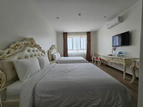 a large white bedroom with two beds and a desk at Grand Hill Hotel & Apartment in Hai Phong
