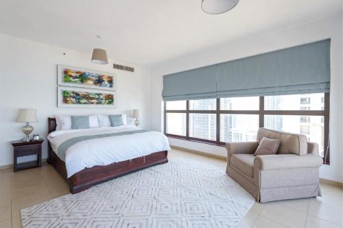 een slaapkamer met een bed, een bank en een stoel bij Stunning Marina & Sea View 4 Bedroom Apartment, Murjan 6 Jumeriah Beach in Dubai