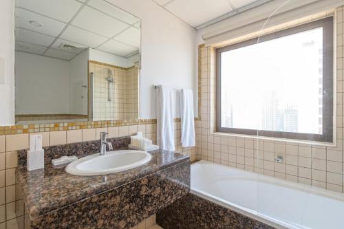 een badkamer met een wastafel, een bad en een raam bij Stunning Marina & Sea View 4 Bedroom Apartment, Murjan 6 Jumeriah Beach in Dubai