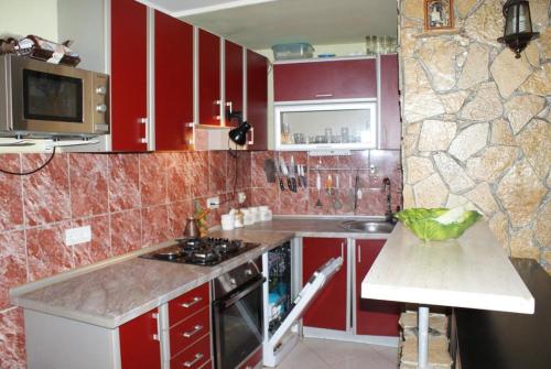 een keuken met rode kasten en een aanrecht bij Aurora in Sutomore
