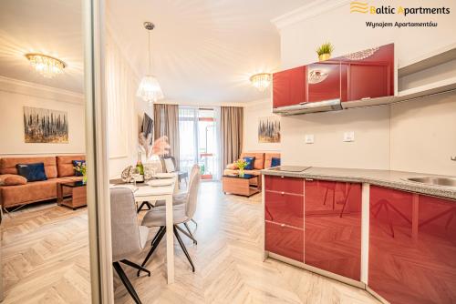 Il comprend une cuisine et un salon avec une table et des chaises. dans l'établissement Baltic Apartments - Róża Wiatrów, à Świnoujście