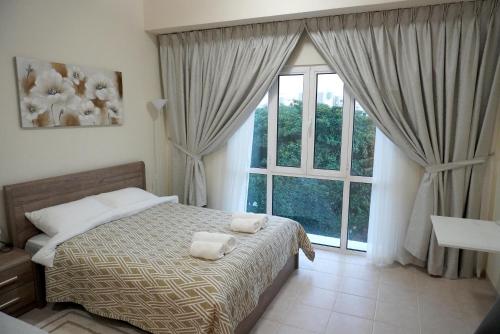 a bedroom with a bed and a large window at Brand New Cozy Studio Apatrtment in Dubai