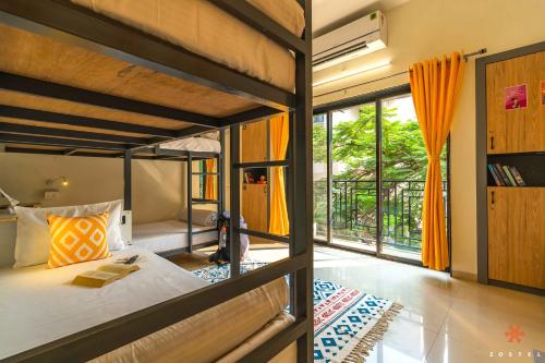 1 dormitorio con 2 literas y balcón en Zostel Pune (Viman Nagar) en Pune