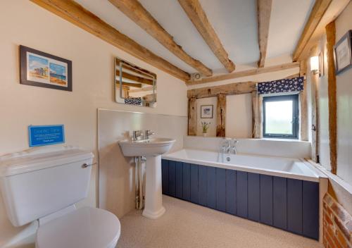 a bathroom with a toilet and a tub and a sink at Tithe Barn at Wattisham Hall in Wattisham