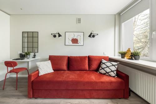 a red couch in a living room with a table at Cozy apartment in Zverynas in Vilnius
