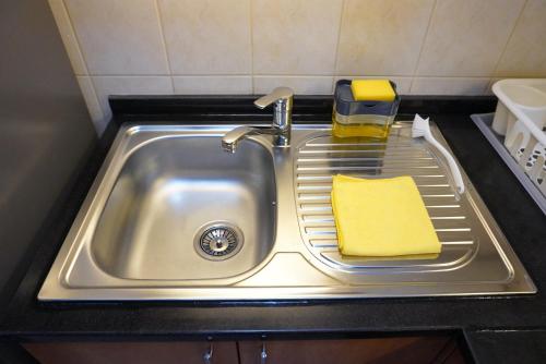 zlew kuchenny z gąbką i żółtym ręcznikiem w obiekcie Brand New Cozy Studio Apatrtment w Dubaju