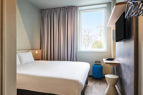 um quarto de hotel com uma cama branca e uma janela em Hôtel Ibis Budget Nantes Ouest Atlantis Couëron em Couëron