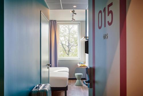 ein Zimmer mit einem Fenster und einem weißen Stuhl in einem Zimmer in der Unterkunft Hôtel Ibis Budget Nantes Ouest Atlantis Couëron in Couëron