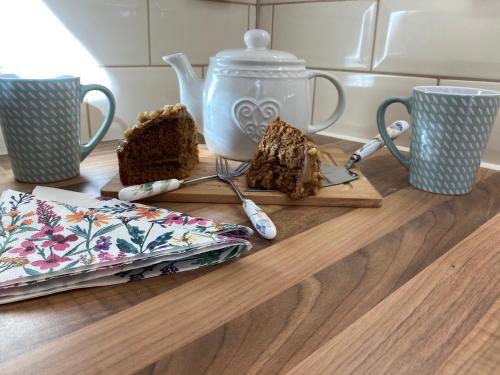 a table with a cutting board with cake and two cups at The Stables in Metheringham