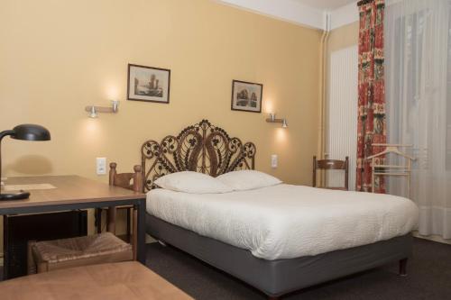 a bedroom with a bed with a desk and a bed sidx sidx sidx at Cit'Hotel Aéro-Hotel in Le Blanc-Mesnil