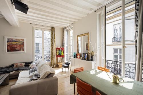 a living room with a couch and some windows at Cosy appart Odéon Saint Germain in Paris