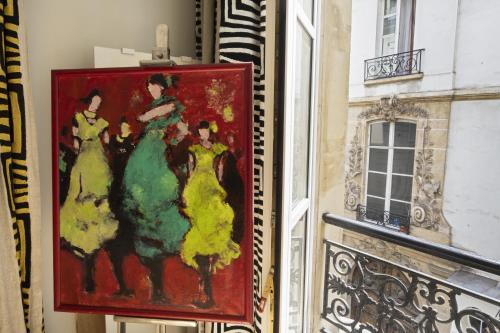 a painting hanging on a wall next to a window at Cosy appart Odéon Saint Germain in Paris