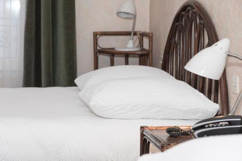 a bed with a pillow and a lamp on a table at Cit'Hotel Aéro-Hotel in Le Blanc-Mesnil