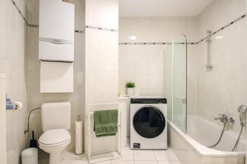 a white bathroom with a washing machine in a shower at Charmant Gents app met alle comfort en vlot bereikbaar in Ghent