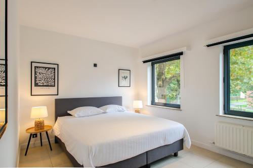 una camera bianca con un letto e due finestre di Charmant Gents app met alle comfort en vlot bereikbaar a Gand