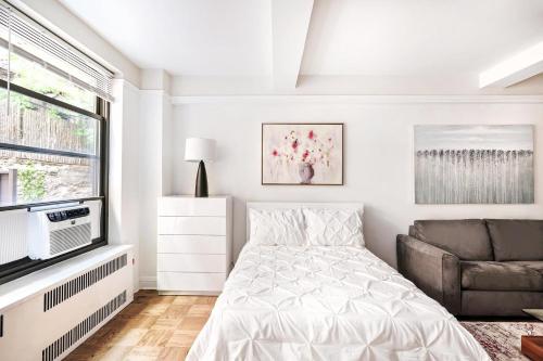 a white bedroom with a bed and a couch at Cozy Studio Apartment in New York