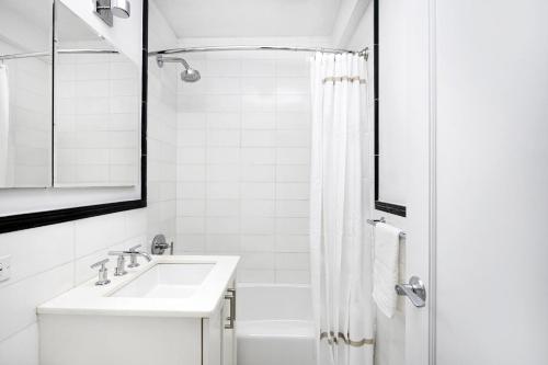 a white bathroom with a sink and a shower at Cozy Studio Apartment in New York