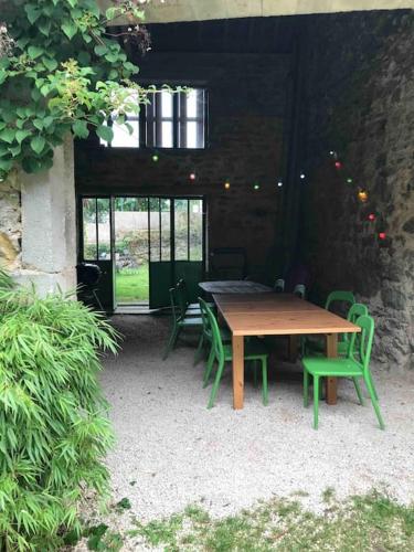 une table en bois et des chaises vertes dans un bâtiment dans l'établissement GITE LES PETITS GALETS Bourgogne du Sud, à Saint-Maurice-lès-Couches