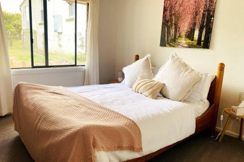 una camera da letto con un letto con lenzuola bianche e una finestra di Skyview Cottage a Leura