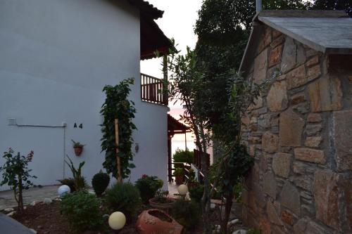 a garden with plants and a stone building at Alisaxni Seaside Studio in Agios Ioannis Pelio