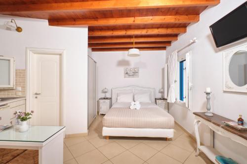 a white bedroom with a bed and a table at Amorgion Hotel in Katapola