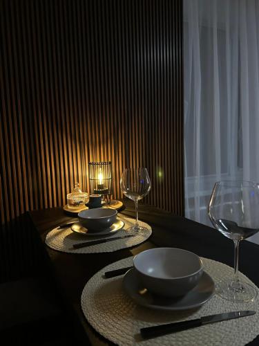 a table with two plates and wine glasses on it at Vienibas Apartaments in Krāslava