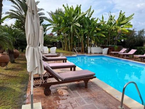 a swimming pool with lounge chairs and an umbrella at Akamas Bay View Villa in Polis Chrysochous