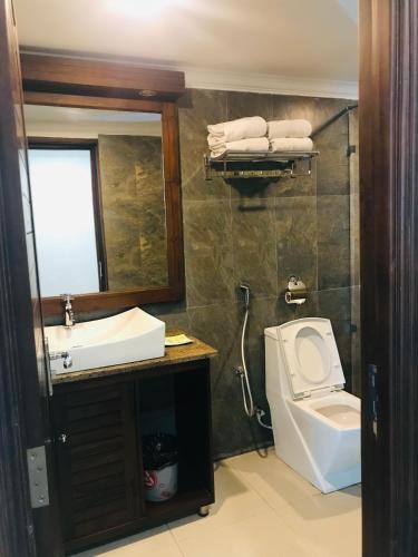 a bathroom with a sink and a toilet and a mirror at Galaxy Grand Hotel in Nuwara Eliya