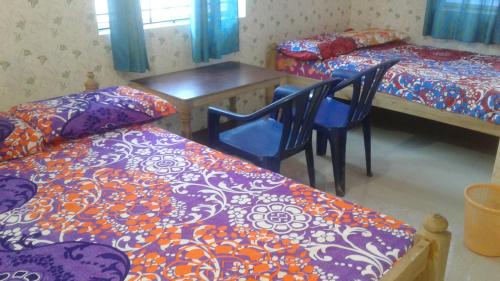 Habitación con 2 camas, mesa y sillas en Happy Tourist Home Neyyardam, en Parattipalli