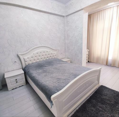 ein weißes Schlafzimmer mit einem weißen Bett und einem Fenster in der Unterkunft Комфортная двухкомнатная квартира in Bischkek