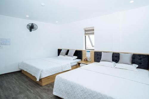 two beds in a room with white walls at Thanh Măng Hotel in Quang Ninh