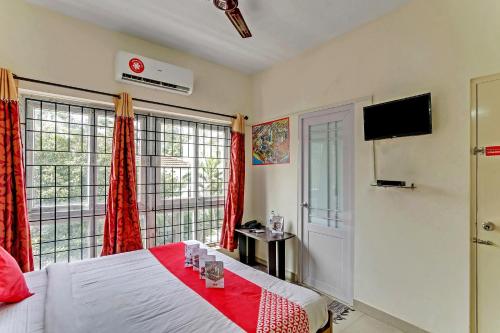 um quarto com uma cama com cortinas vermelhas e uma televisão em OYO Flagship 15148 Sky Pix Near Kasi Talkies em Chennai