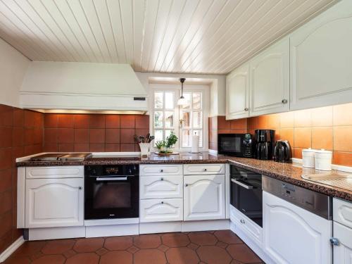 a kitchen with white cabinets and black appliances at Ferienhaus REETselig mit Pool Sauna in Klein Barkau