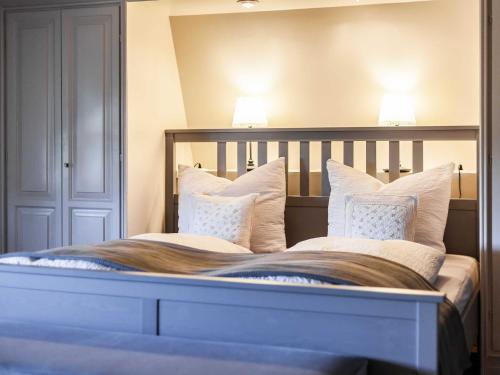 a large bed with white pillows and two lamps at Ferienhaus REETselig mit Pool Sauna in Klein Barkau