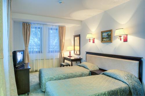 Cette chambre comprend deux lits et une télévision. dans l'établissement MPM Family Hotel Merryan, à Pamporovo