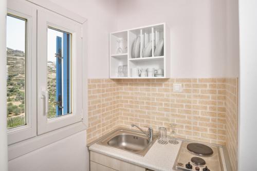 a kitchen with a sink and a window at Amorgion Village in Katapola
